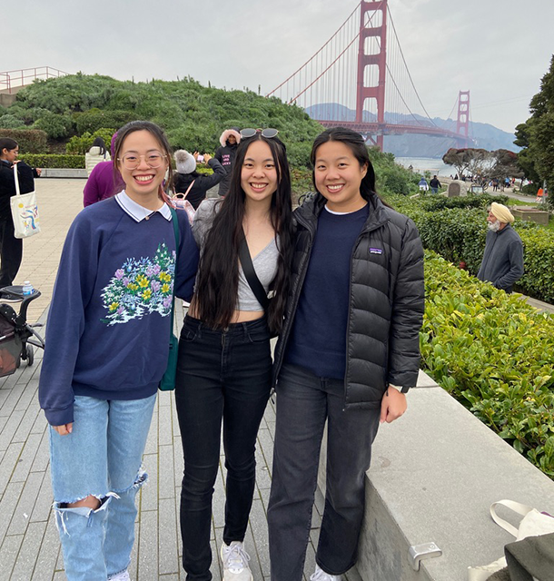 Three young women pose for a picture with the Golden Gate Bridge in the background