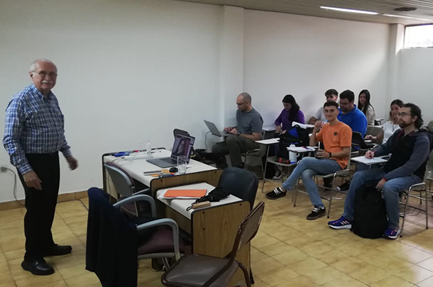 Ignacio Grossmann stands in front of 9 college students seated in a small classroom