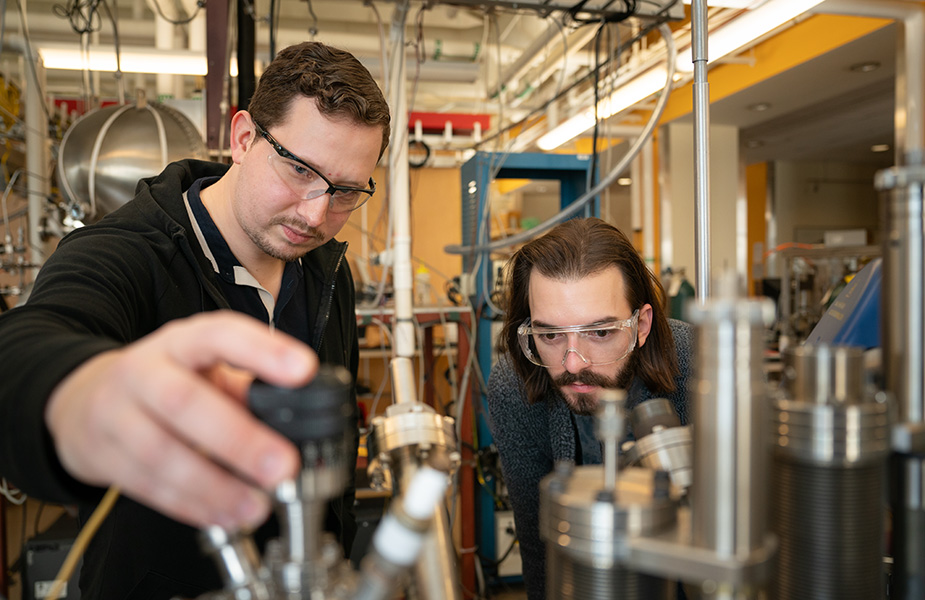 Two men look at a piece of scientific equipment in a laboratory.