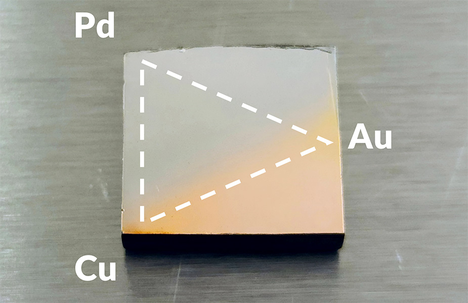 A small, square piece of metal. The top left half is light gray and the bottom right half is a pale copper color. In the photos, a dashed-line triangle has been drawn on top of the square with the corners labeled P.d., A.u., and C.u.