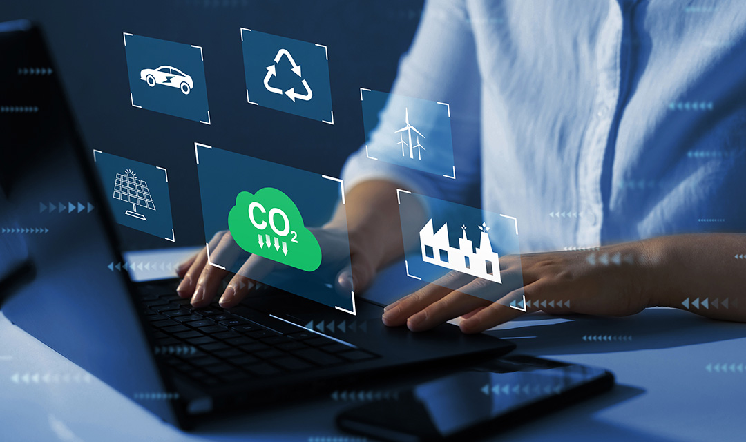 A pair of hands rests on a laptop keyboard. Floating above the keyboard are graphics representing decarbonization.