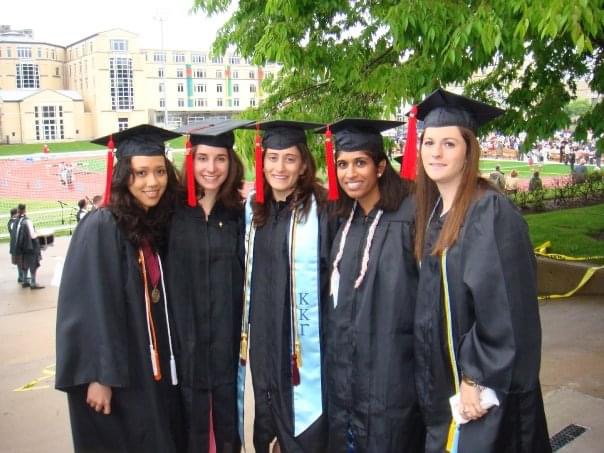 Five young women wearing regalia pose for a photo.