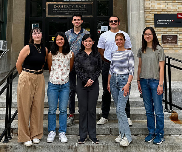 7 adults pose for a group photo in front of Doherty Hall